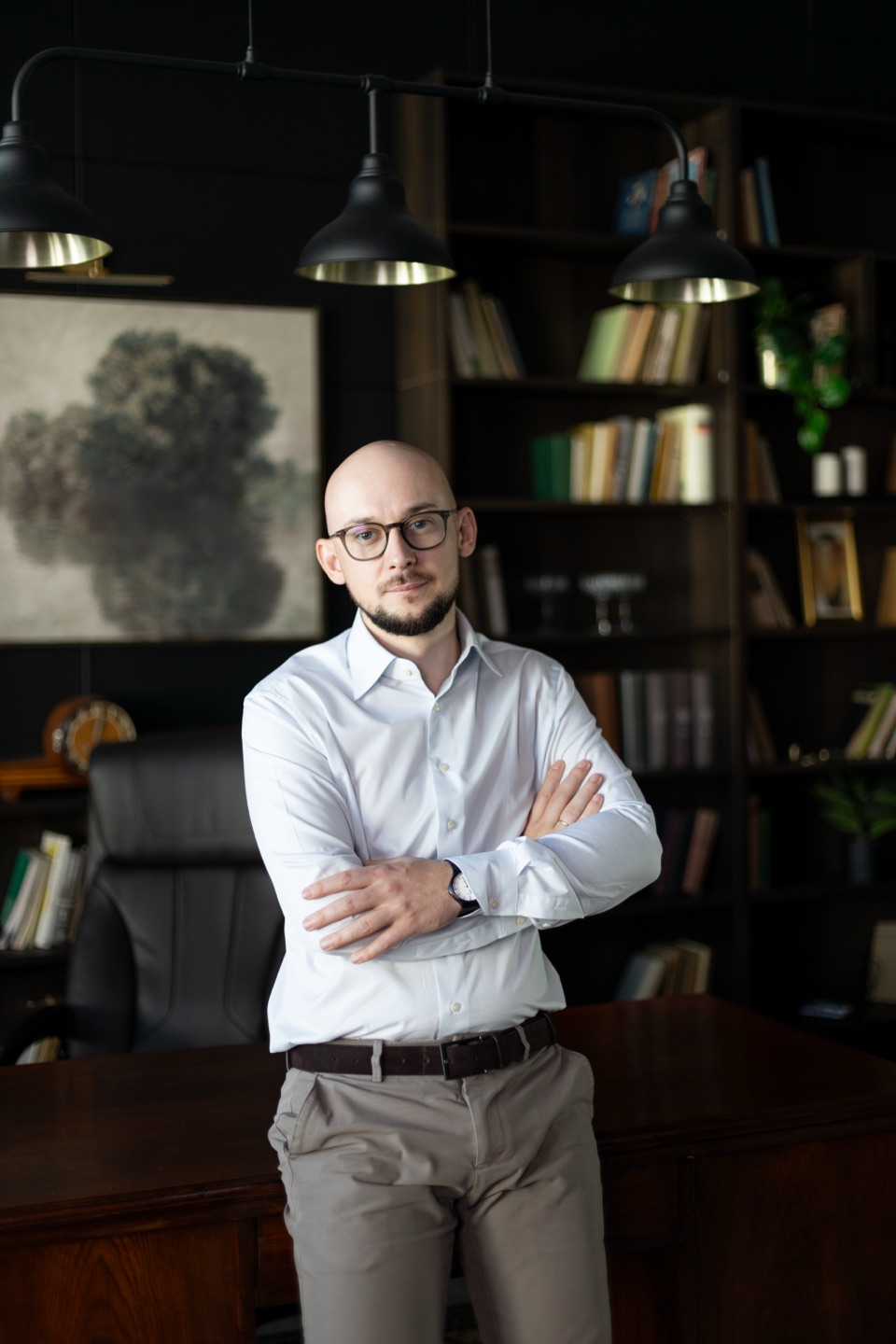 Jędrzej Anuszkiewicz-Michałek z założonymi rękami w bibliotece